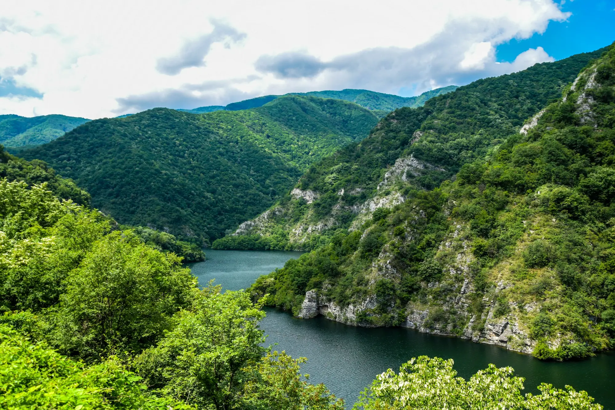 Зелени планини и река под синьо небе
